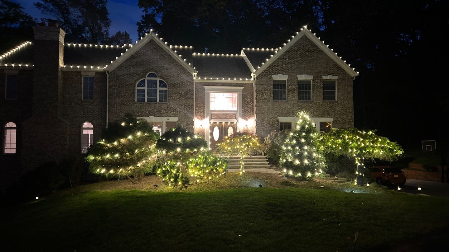 Brick home with roofline lights and glowing shrubs and trees
